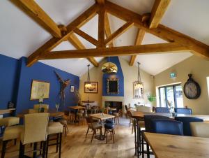 霍姆弗斯The Pickled Pheasant的一间拥有蓝色墙壁和木桌及椅子的用餐室