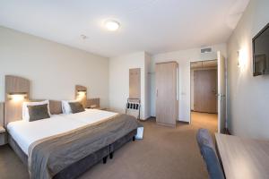 坎珀兰Fletcher Wellness-Hotel Kamperduinen的卧室配有一张白色的大床和一张桌子
