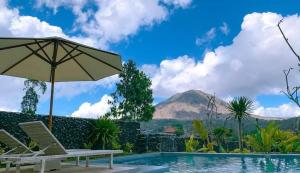 BaturajaHost @ Volcano的一个带桌椅和遮阳伞的游泳池