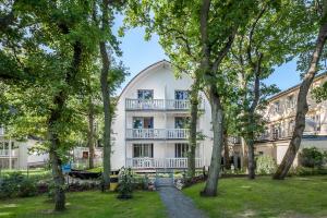 博尔滕哈根Strandvilla Scholle - Dorsch Wohnung 02的前面有树木的白色大建筑
