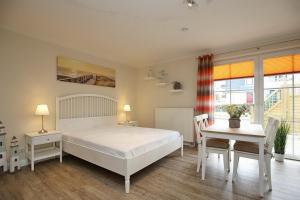 博尔滕哈根Strandvilla Krabbe Wohnung 08的卧室配有白色的床和桌椅