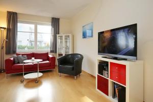 博尔滕哈根Dünenblick Wohnung 35的客厅配有红色沙发和平面电视
