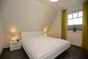 博尔滕哈根Reethaus Am Mariannenweg 09a的卧室设有一张白色大床和一扇窗户。