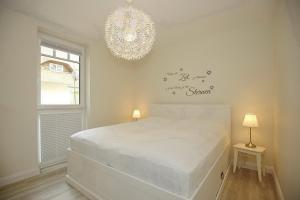 博尔滕哈根Strandvilla Scholle - Lachs Wohnung 01的卧室配有白色的床和吊灯。