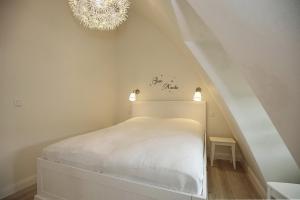 博尔滕哈根Strandvilla Scholle - Aal Wohnung 06的卧室配有白色的床和吊灯。
