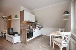 博尔滕哈根Strandvilla Krabbe Wohnung 13的厨房配有白色橱柜、桌子和炉灶。