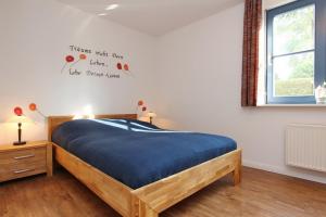 博尔滕哈根Papillon Wohnung 04-1的一间卧室配有一张带蓝色床单的床和一扇窗户。