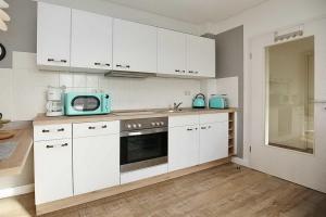 博尔滕哈根Haffblick Wohnung 42的厨房配有白色橱柜和蓝色微波炉