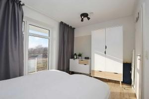 博尔滕哈根Haffblick Wohnung 42的白色的卧室设有一张大床和一个窗户