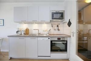 博尔滕哈根Dünenblick Wohnung 12的白色的厨房配有水槽和微波炉