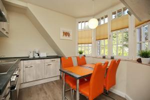 博尔滕哈根Strandvilla Krabbe Wohnung 05的厨房配有桌子和橙色椅子