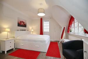 博尔滕哈根Strandvilla Krabbe Wohnung 05的卧室配有白色的床和红色地毯。