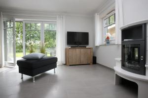 博尔滕哈根Reethaus Am Mariannenweg 11a的一间带电视和椅子的客厅