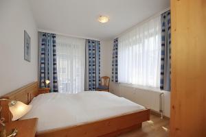 博尔滕哈根Dünenblick Wohnung 43的卧室设有白色大床和窗户。