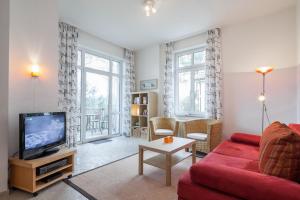 博尔滕哈根Villa Triton Wohnung 02的客厅配有红色沙发和电视