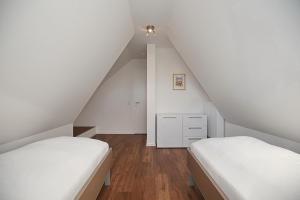 博尔滕哈根Reethaus Am Mariannenweg 06b的阁楼卧室设有2张床和白色的墙壁。