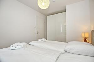 海利根达姆Linden-Palais Wohnung 25的白色卧室设有2张白色床和吊灯