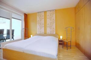 博尔滕哈根Likedeeler Wohnung 12的卧室配有白色的床和黄色的墙壁