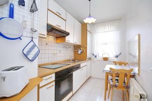 博尔滕哈根Sünnslag Wohnung 058的厨房配有白色橱柜、水槽和桌子