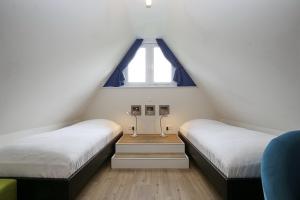 博尔滕哈根Reethaus Am Mariannenweg 11b的阁楼卧室设有两张床和窗户。