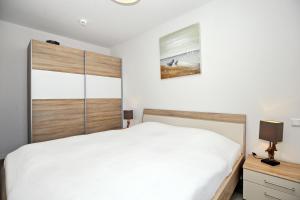 海利根达姆Residenz von Flotow Wohnung 15的卧室配有白色的床和木制床头板