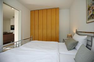 海利根达姆Linden-Palais Wohnung 39的卧室配有白色的床和木制床头板