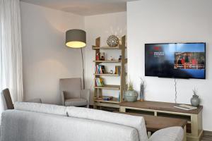 海利根达姆Linden-Palais Wohnung 14的客厅配有沙发和墙上的电视