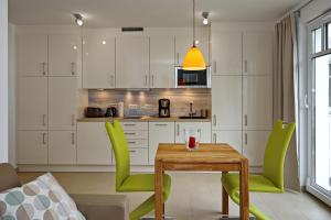 海利根达姆Linden-Palais Wohnung 27的厨房配有木桌和绿色椅子