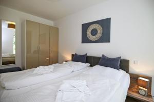 海利根达姆Linden-Palais Wohnung 08的一间卧室配有两张白色大床和蓝色枕头
