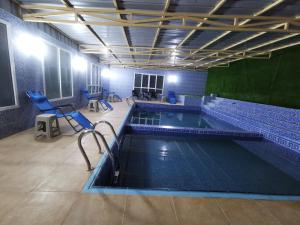 Al ‘AynVilla Salassel Al Jabal Al Akhdar فلة سلاسل الجبل الأخضر的一个带蓝色椅子的大型游泳池