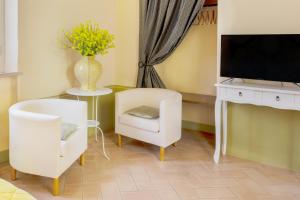 皮恩扎La Chiocarella的客厅配有电视和白色椅子