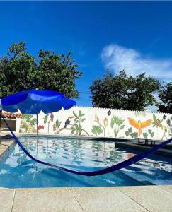 卡波布里奥POUSADA e HOSTEL ARAUNA的一个带蓝色遮阳伞的游泳池,位于墙上