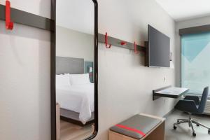劳德代尔堡Avid hotels - Ft Lauderdale Airport - Cruise, an IHG Hotel的一张床铺和一张书桌,镜子
