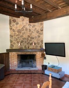 Villanueva del CondeCasa rural Adelaida的客厅设有石制壁炉和平面电视。