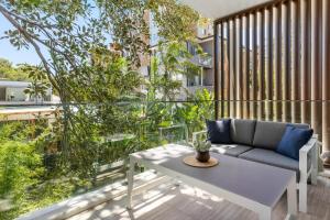 悉尼Azure Apartments by Urban Rest的阳台的天井配有沙发和桌子