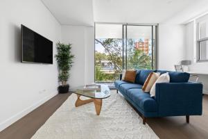 悉尼Azure Apartments by Urban Rest的客厅配有蓝色的沙发和桌子