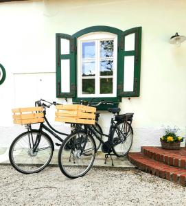 MuggendorfLANDSITZ OBERHOF petit hôtel的两辆自行车停在一座带窗户的建筑旁边