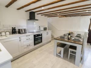 巴拉Cyffdy Cottage - Arenig的厨房配有白色橱柜和木桌