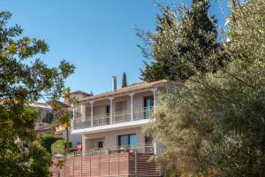 尼基亚娜Nikolas Guest House Villa的带阳台和树木的白色房屋