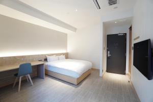石垣岛THIRD ishigakijima的一间卧室配有一张床、一张书桌和一台电视