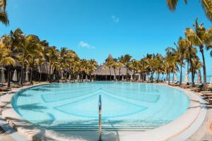勒莫尔尼Paradis Beachcomber Golf Resort & Spa的一座棕榈树游泳池和躺椅