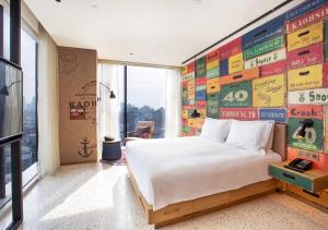 高雄高雄中央公园英迪格酒店的一间卧室设有一张大床和一面标志墙