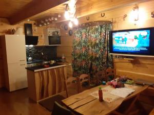 沃尔贾利Domek Letniskowy - M & E的厨房配有桌子,墙上设有电视