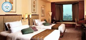 曼谷Rama Gardens Hotel Bangkok - SHA Plus Certified的酒店客房设有两张床和窗户。
