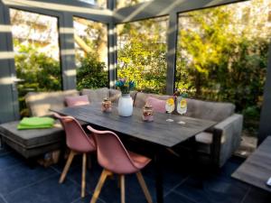 莱比锡奥恩瓦尔德旅馆的庭院里配有一张带粉红色椅子和花瓶的木桌