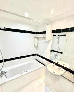 贝尔福德普尔蒂旅馆的白色的浴室设有浴缸和水槽。