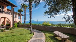 代森扎诺-德尔加达Castello Belvedere Apartments的公园长凳位于房子前面,享有海景