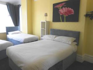 布莱克浦Shore Stay Guest House的一间卧室设有两张床,墙上挂有一幅花画