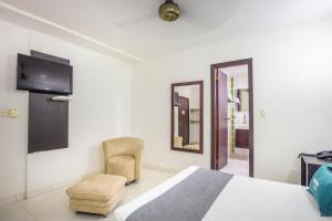 蒙特里亚Ayenda Casa Real的一间卧室配有一张床、一把椅子和电视。
