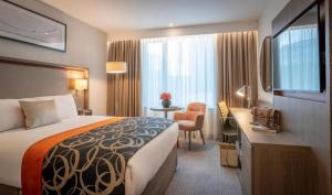 曼彻斯特Clayton Hotel Manchester City Centre的酒店客房配有一张床、一张书桌和一台电视。